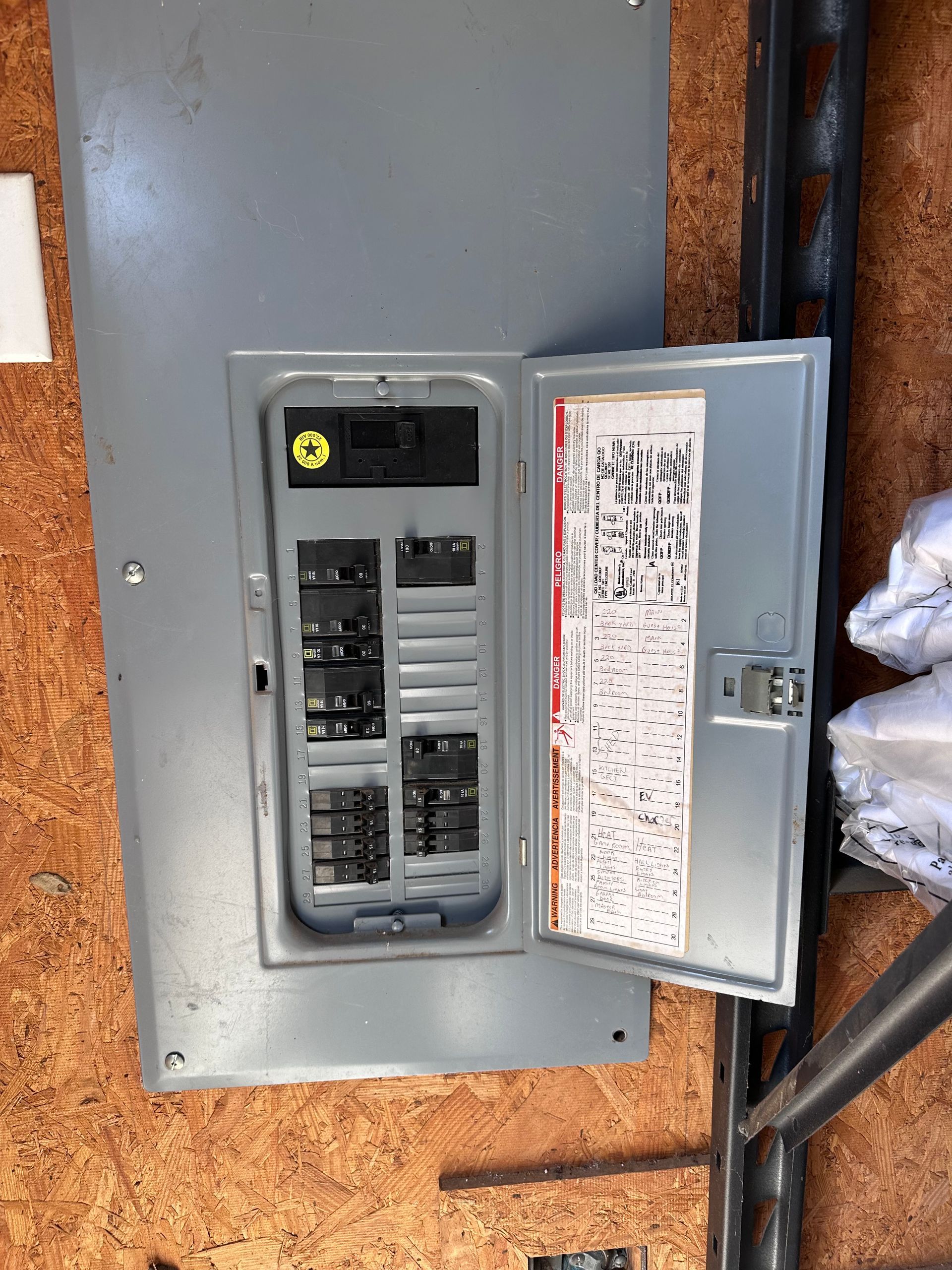Electrical panel with open door, showing circuit breakers and labeling.