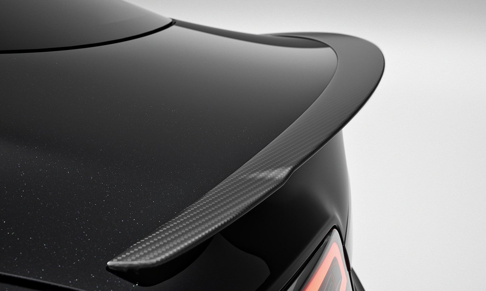 Black car with a carbon fiber spoiler.