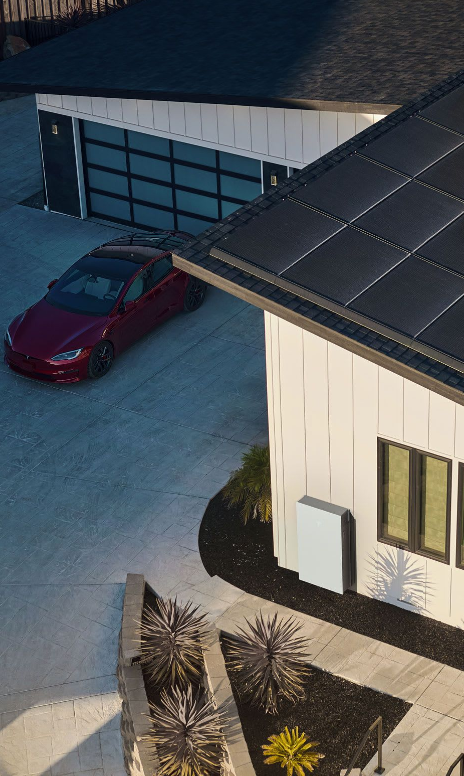 Red car parked near a modern white house with a black roof and garage.