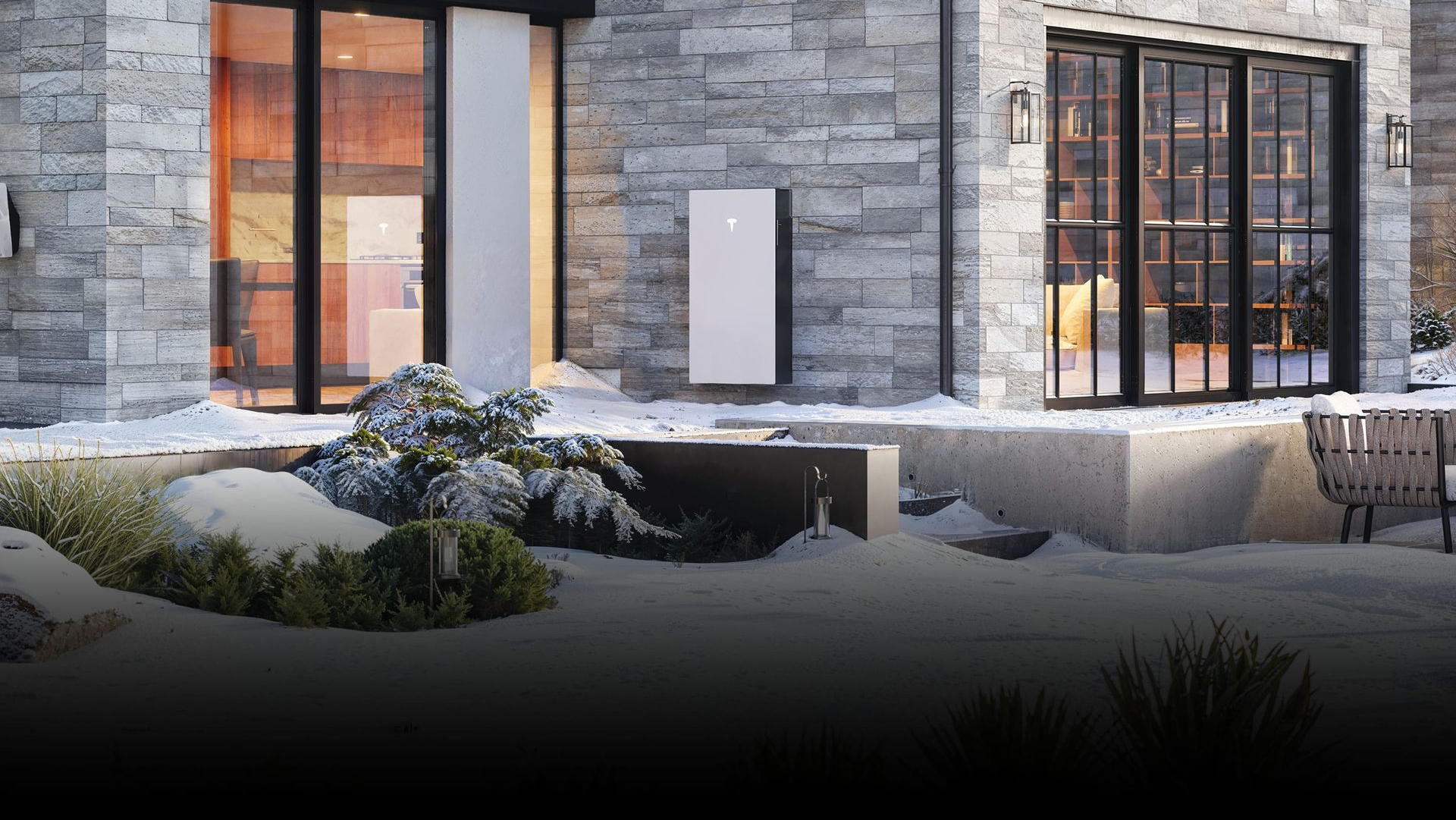 A modern home with a battery storage unit mounted on the exterior wall. Snowy, rocky landscape.