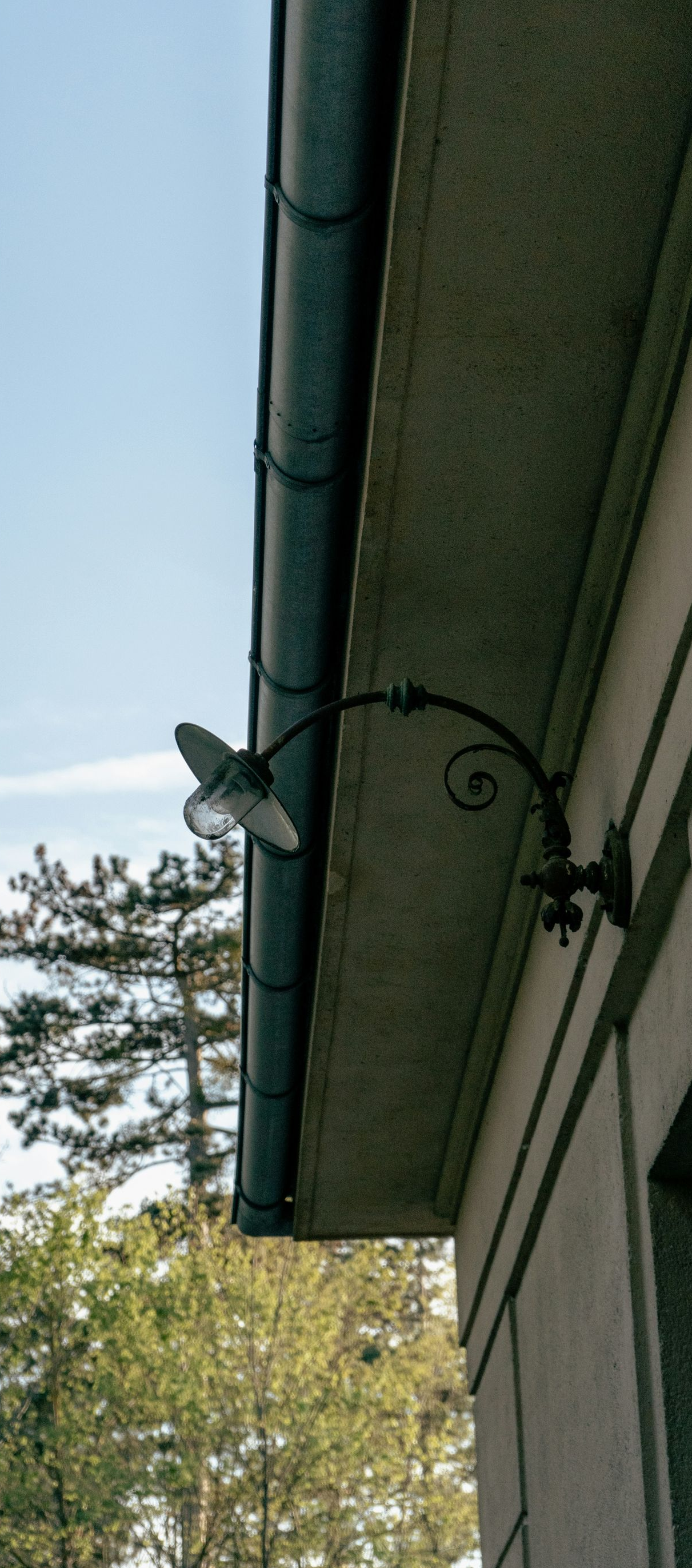 Black decorative outdoor wall lamp on building.