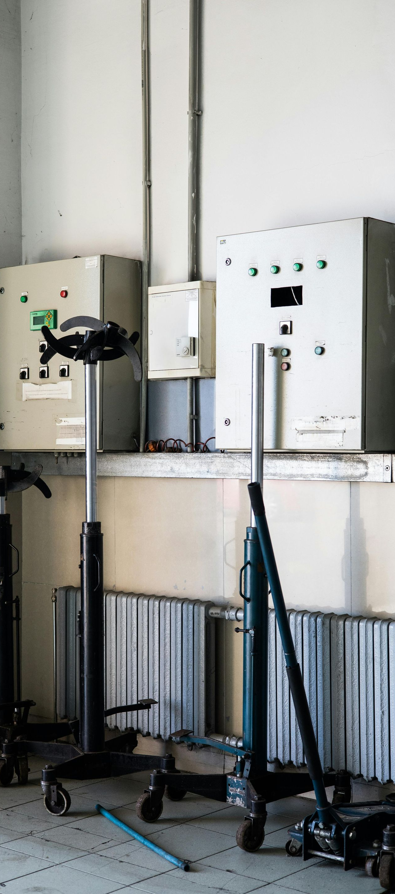 Three black medical stools in a neglected room. Electrical boxes on the wall above a window.
