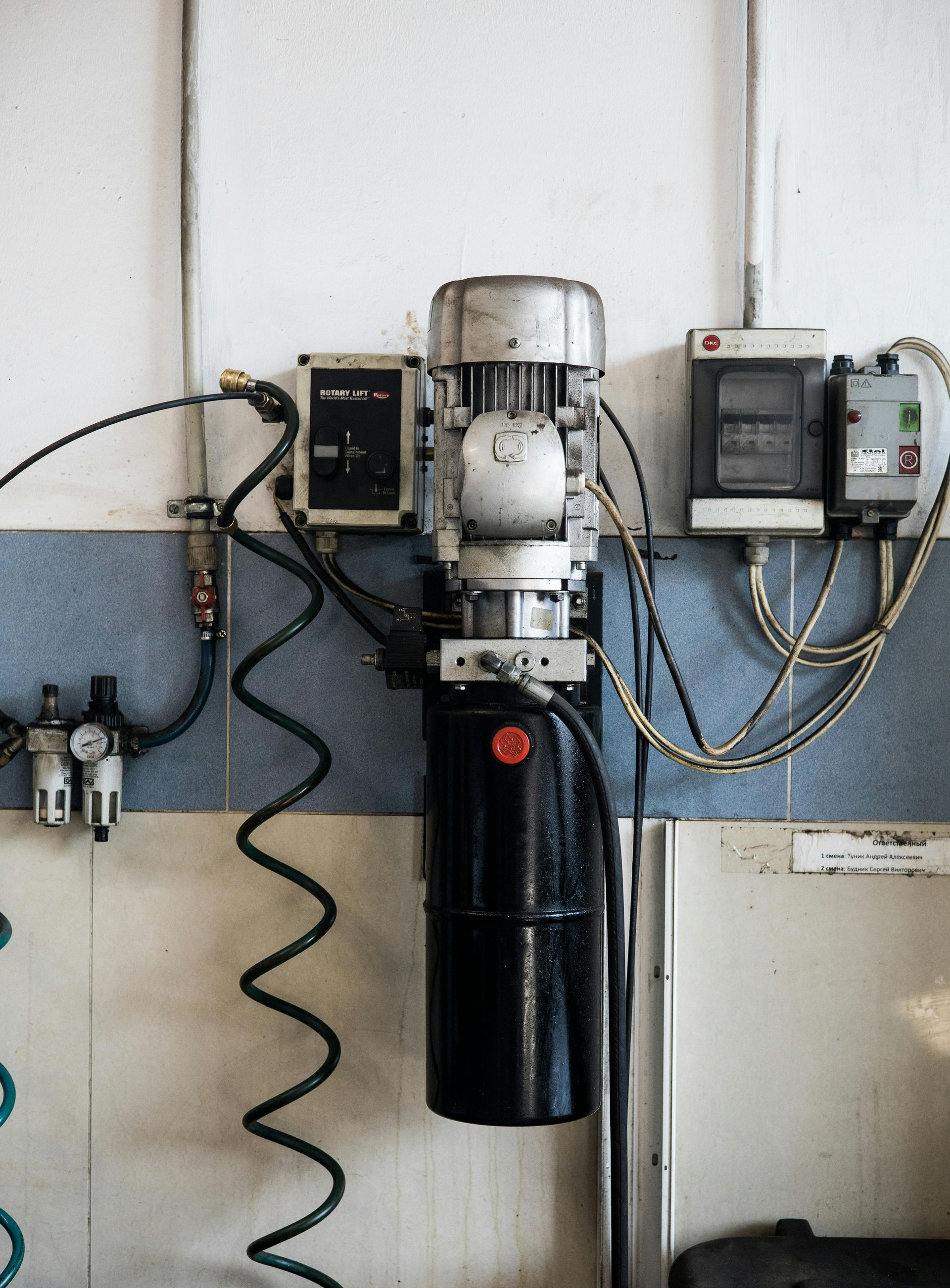 Hydraulic pump equipment mounted on a wall with various electrical components and air lines.