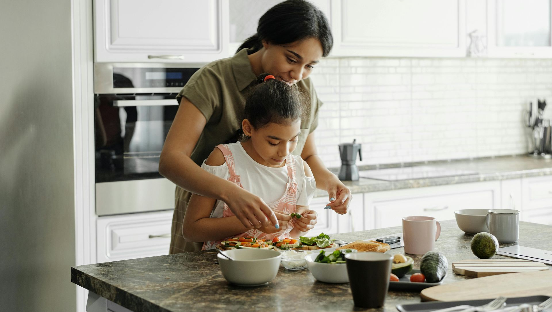 Woman and child preparing food in a kitchen.