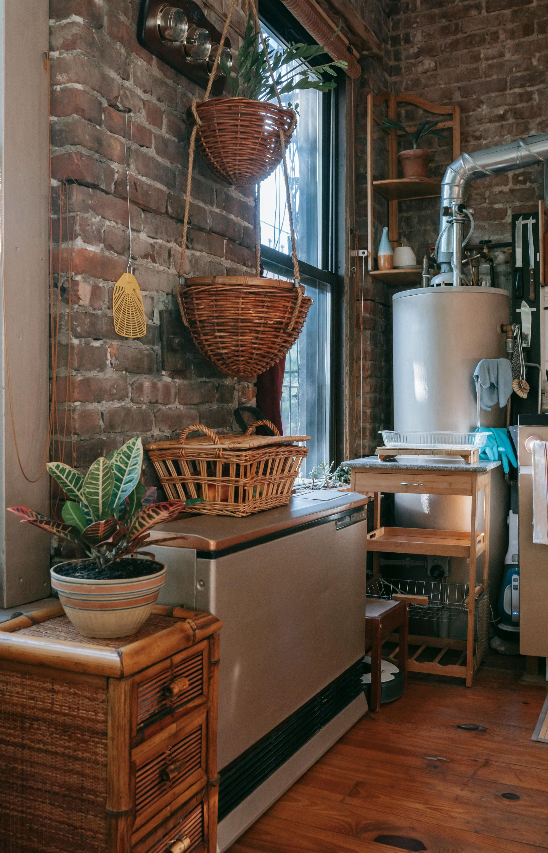 Cozy interior with exposed brick, wicker baskets, and a water heater near a window.