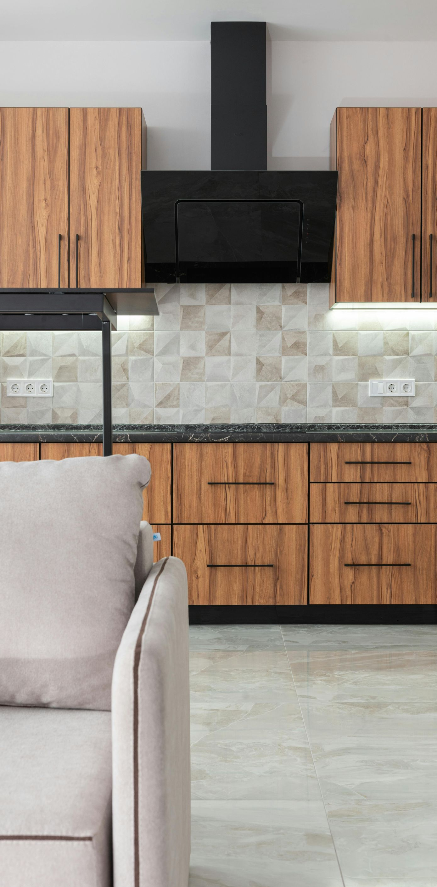 A modern kitchen featuring wooden cabinets and a black range hood.