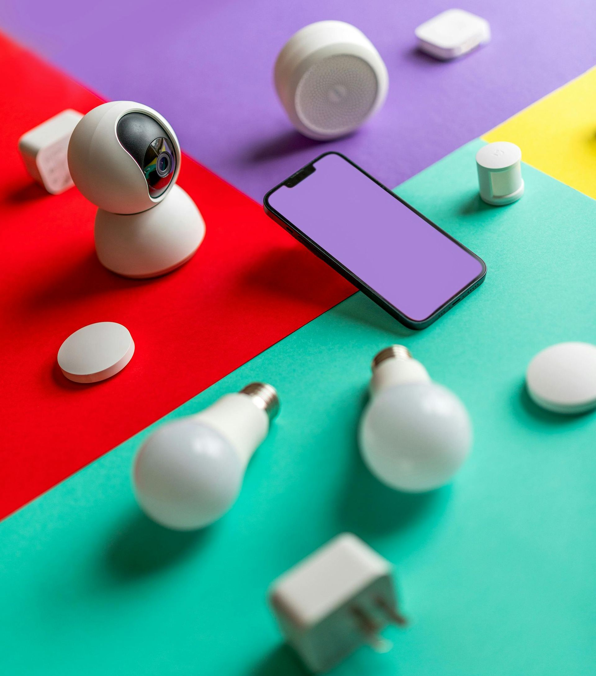 Smart home devices, including a security camera, smartphone, and light bulbs on colorful backgrounds.