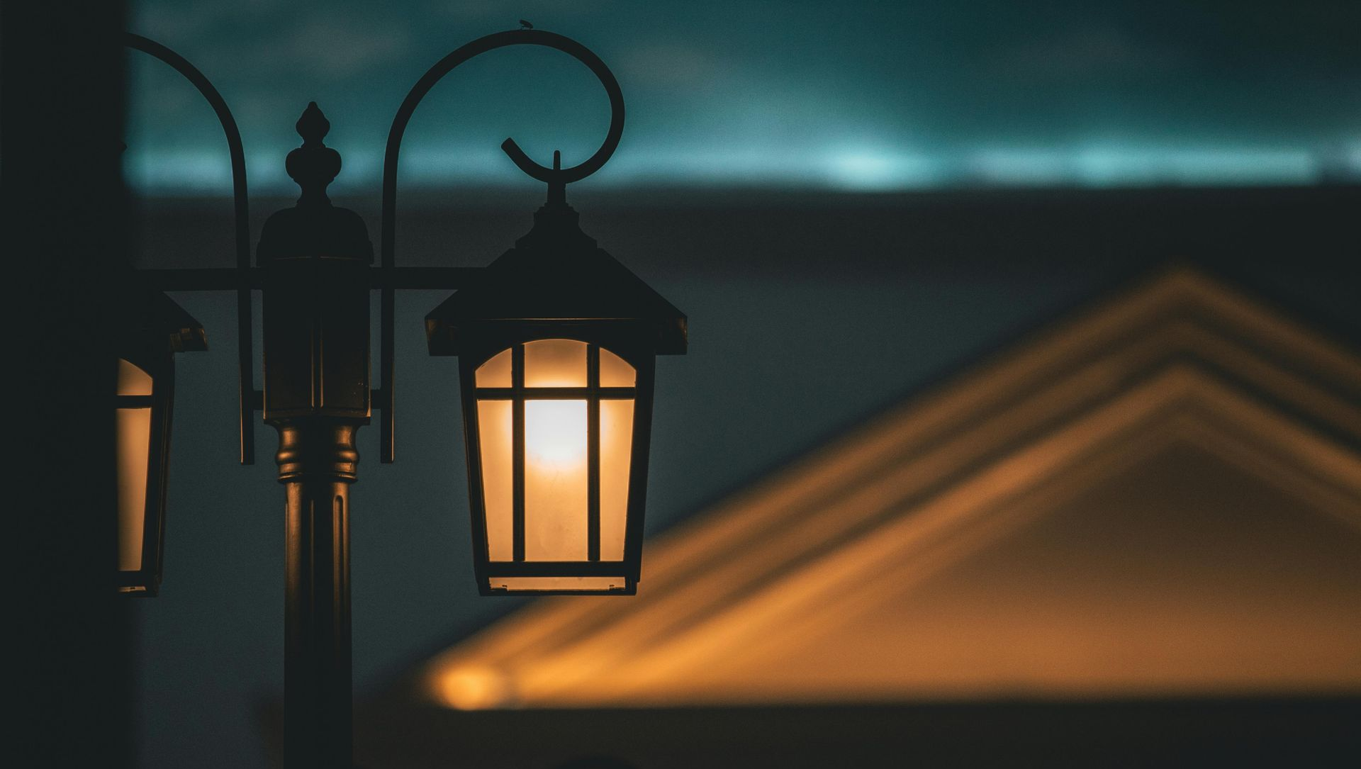 Lantern illuminates a building at night. Dark blue sky with the golden light from the lantern.