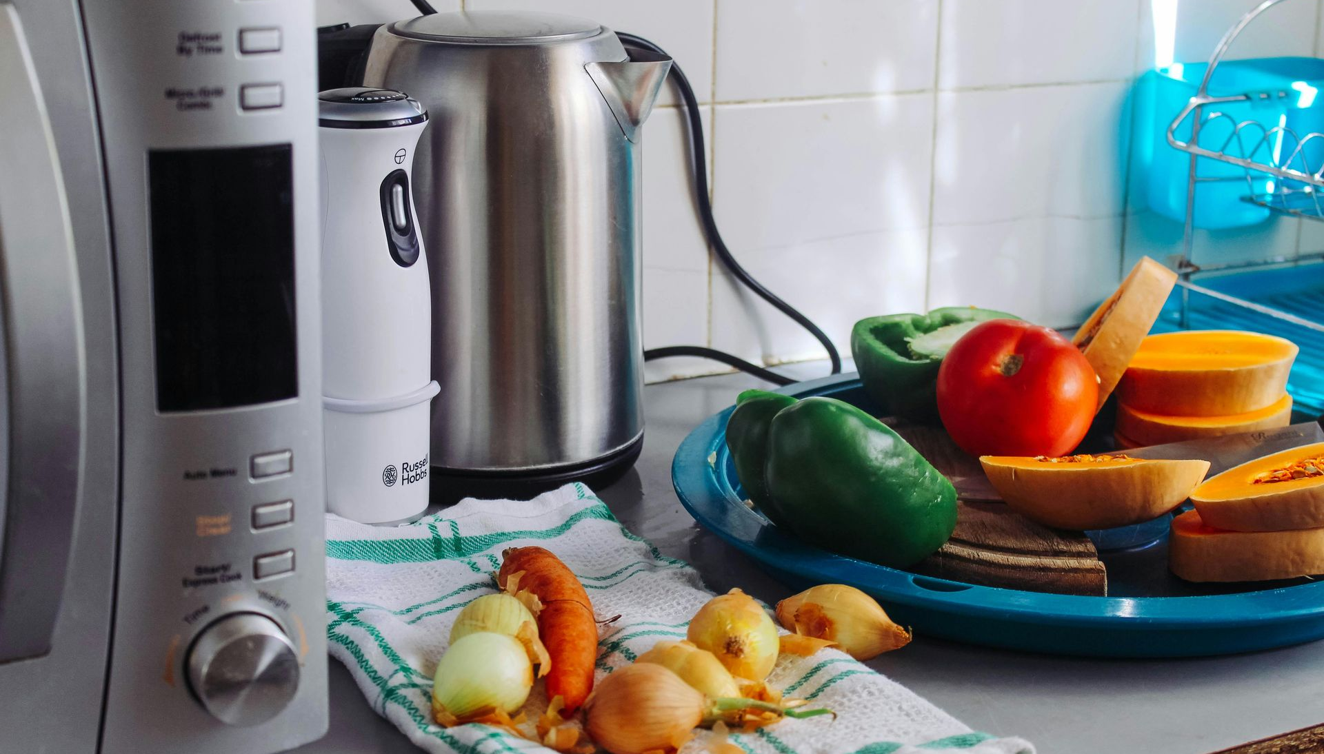 Kitchen counter with microwave, kettle, and vegetables on a plate and towel.