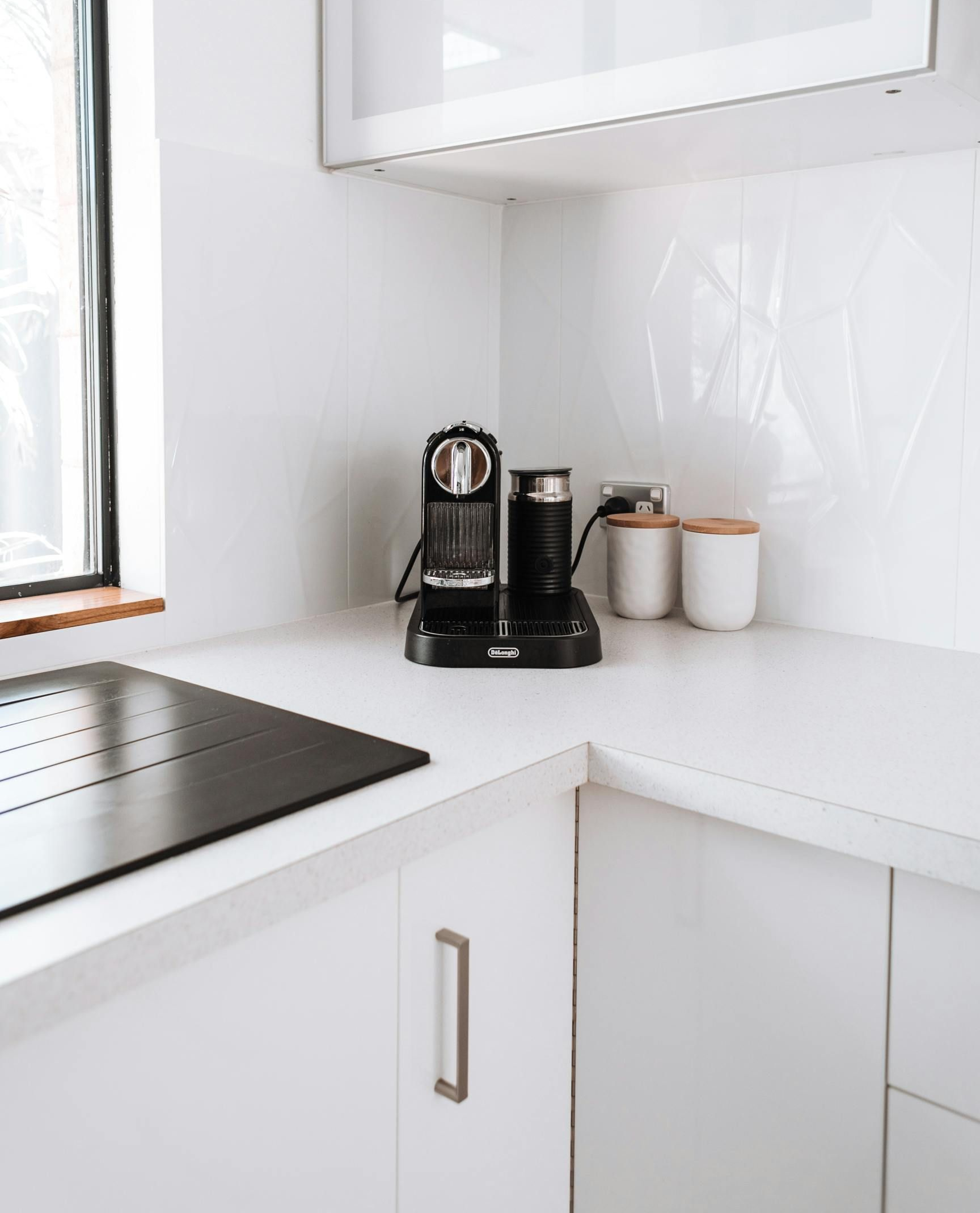White kitchen corner with coffee maker and canisters on countertop.