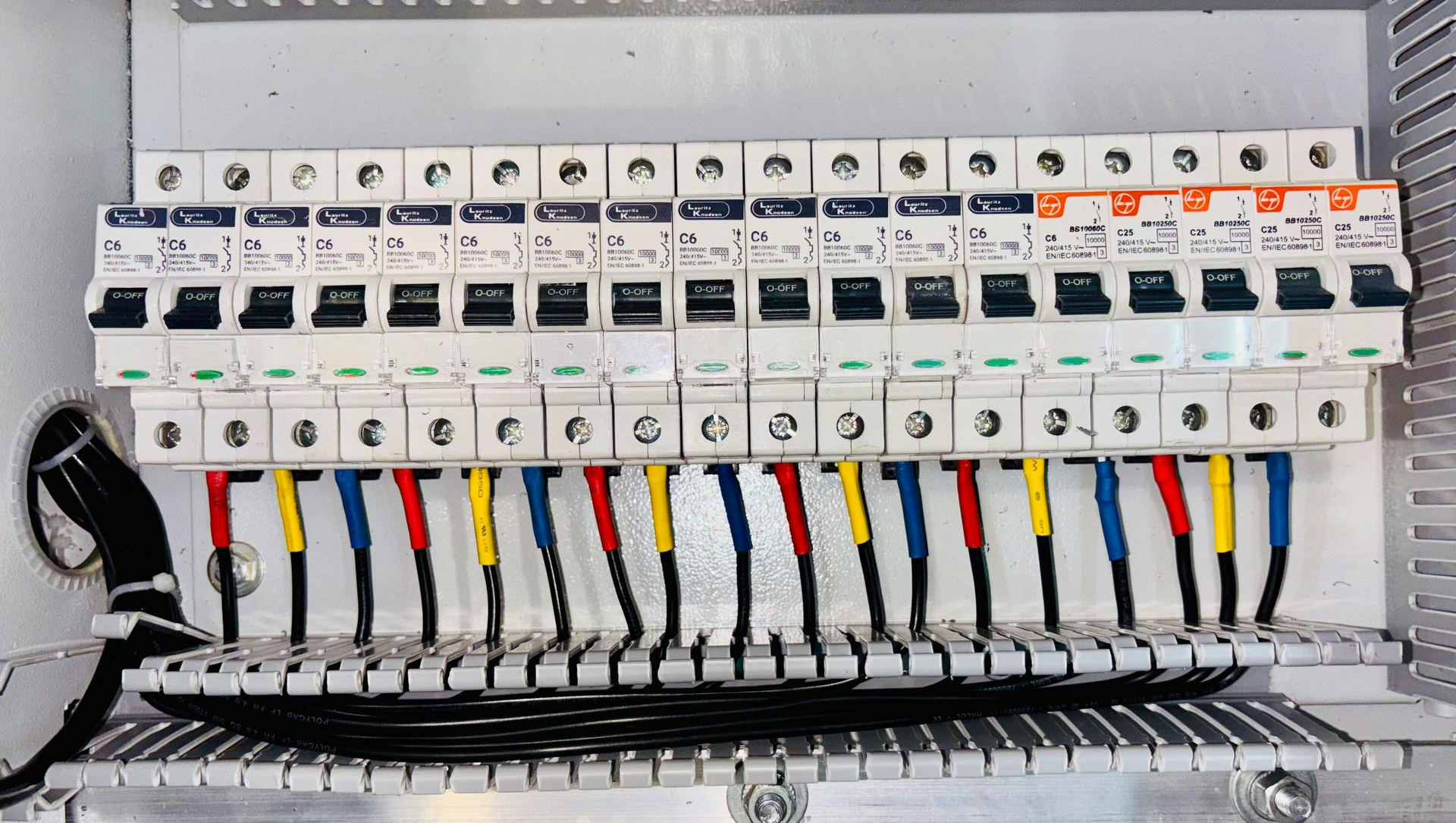 Electrical panel with rows of circuit breakers and colored wires.