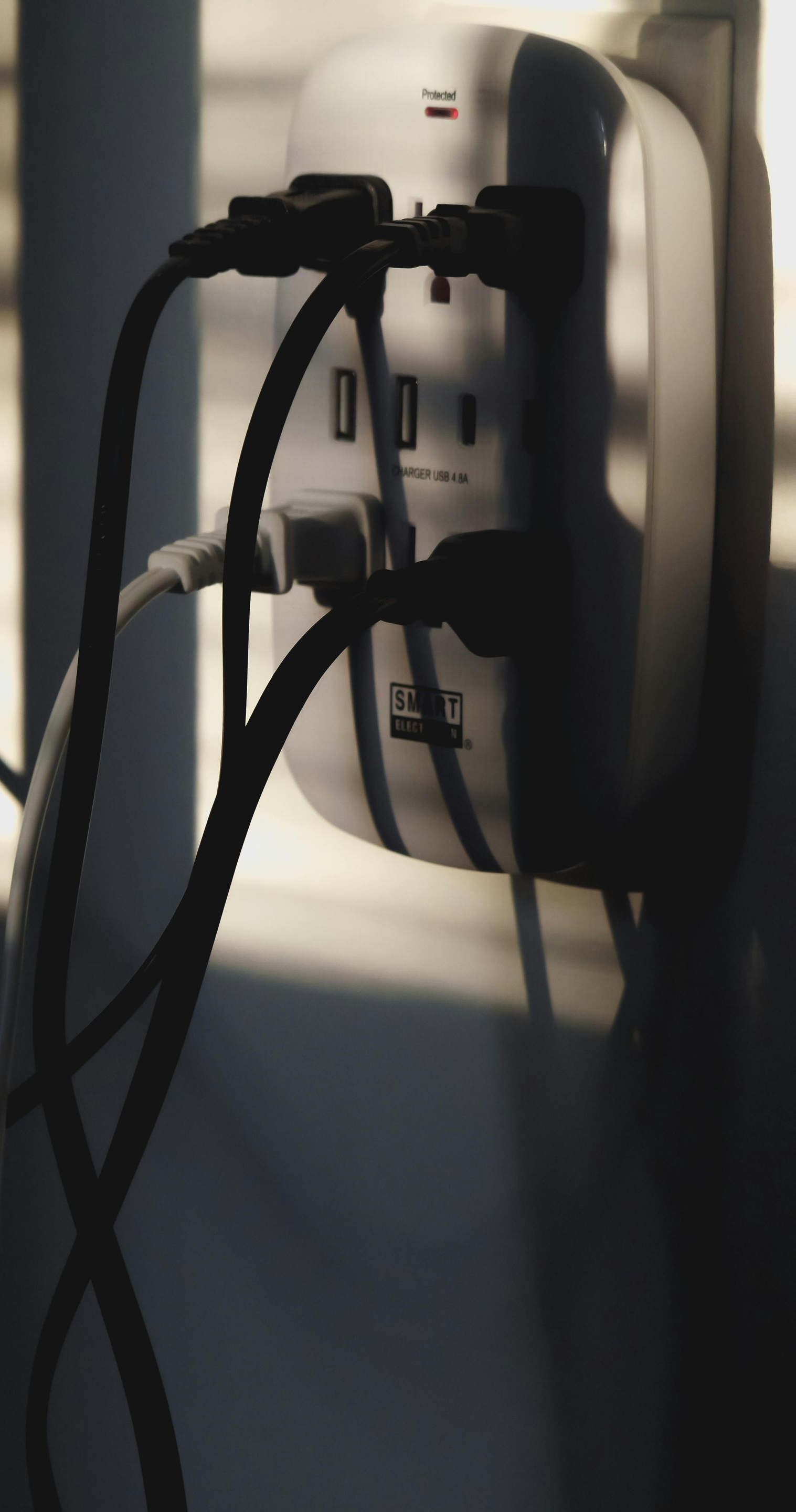 Power strip with several cords plugged in, mounted on a wall.