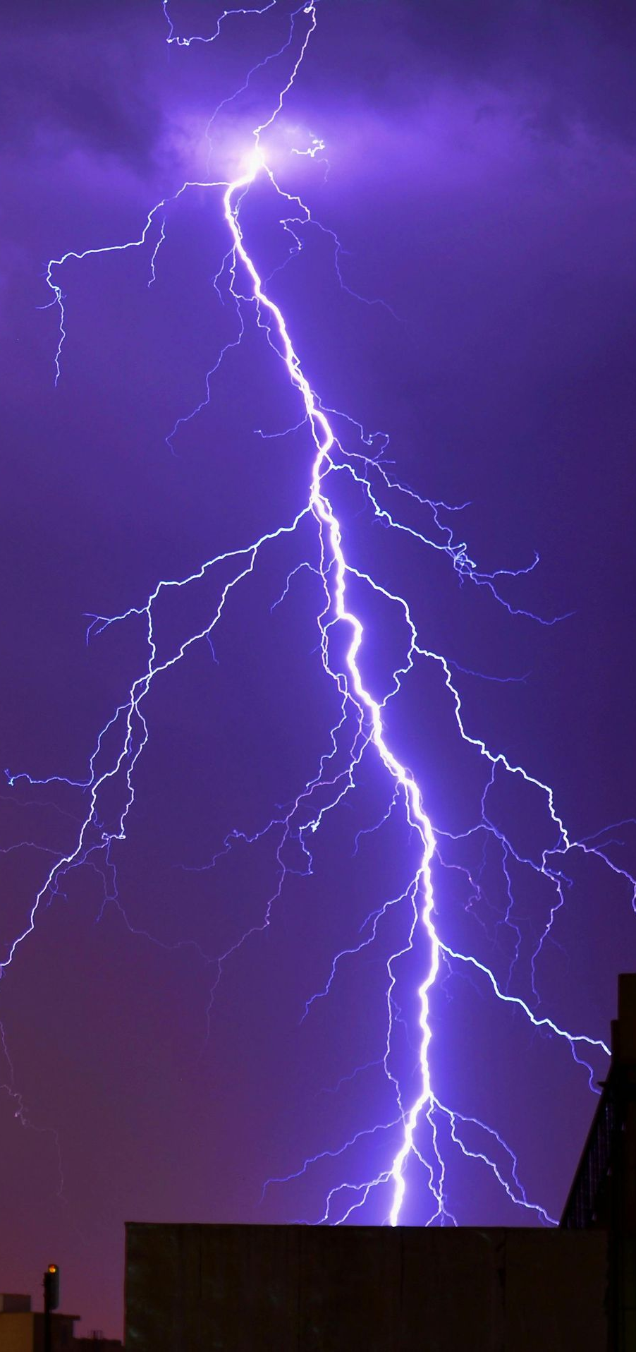 Lightning bolt against a dark purple sky, striking the top of a building.