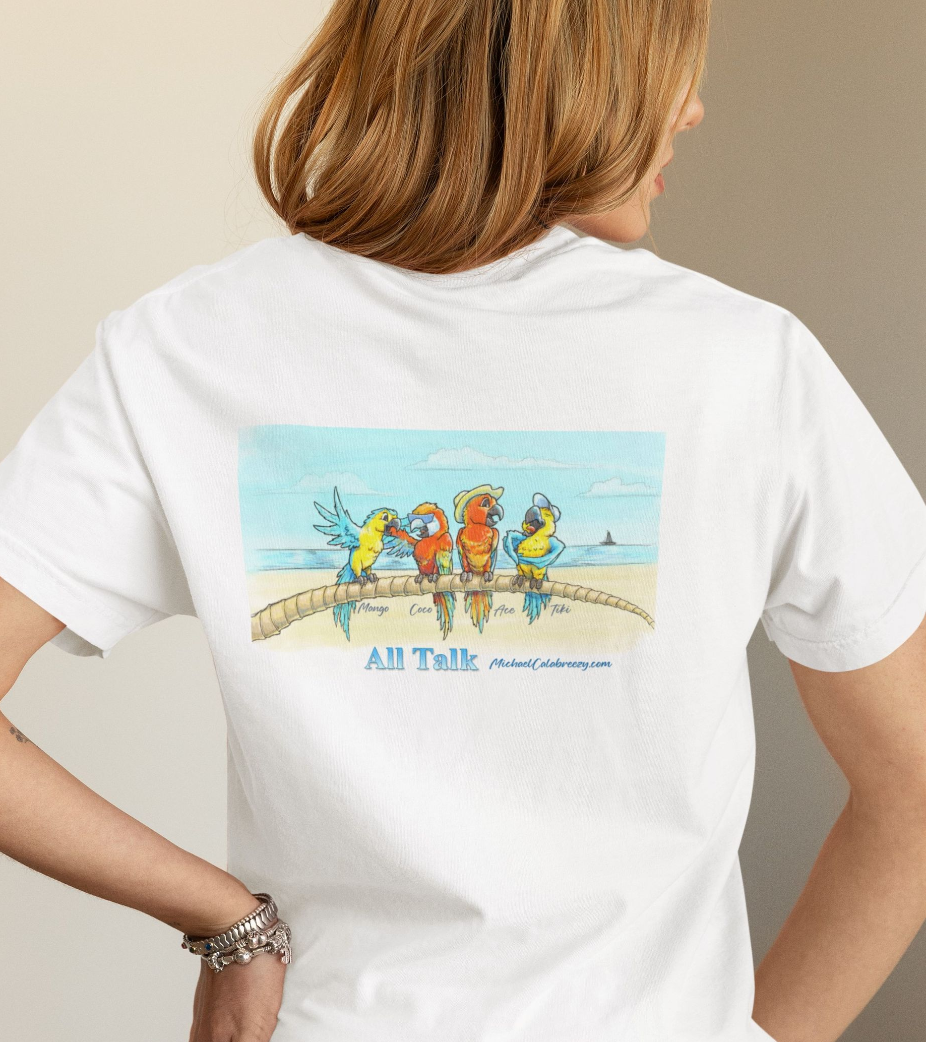 Woman in white t-shirt with a beach scene featuring colorful parrots.