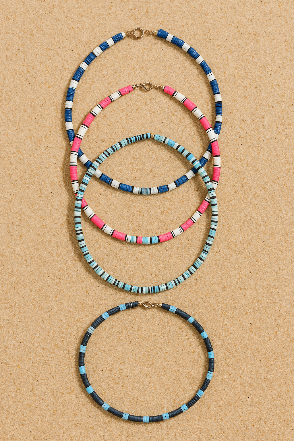 Four colorful beaded necklaces on a light wood surface.