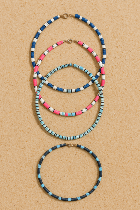 Four colorful beaded necklaces on a light wood surface.