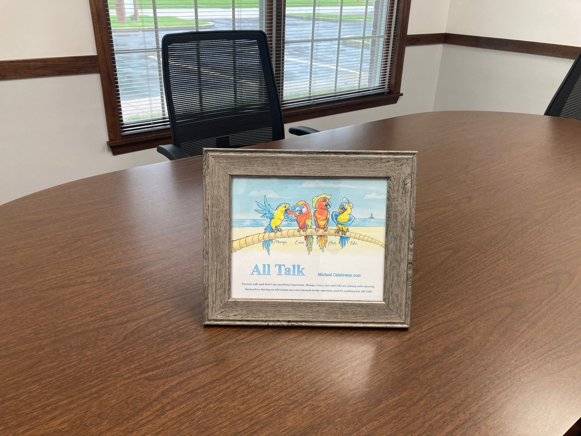 Framed artwork on a brown table with colorful birds, text