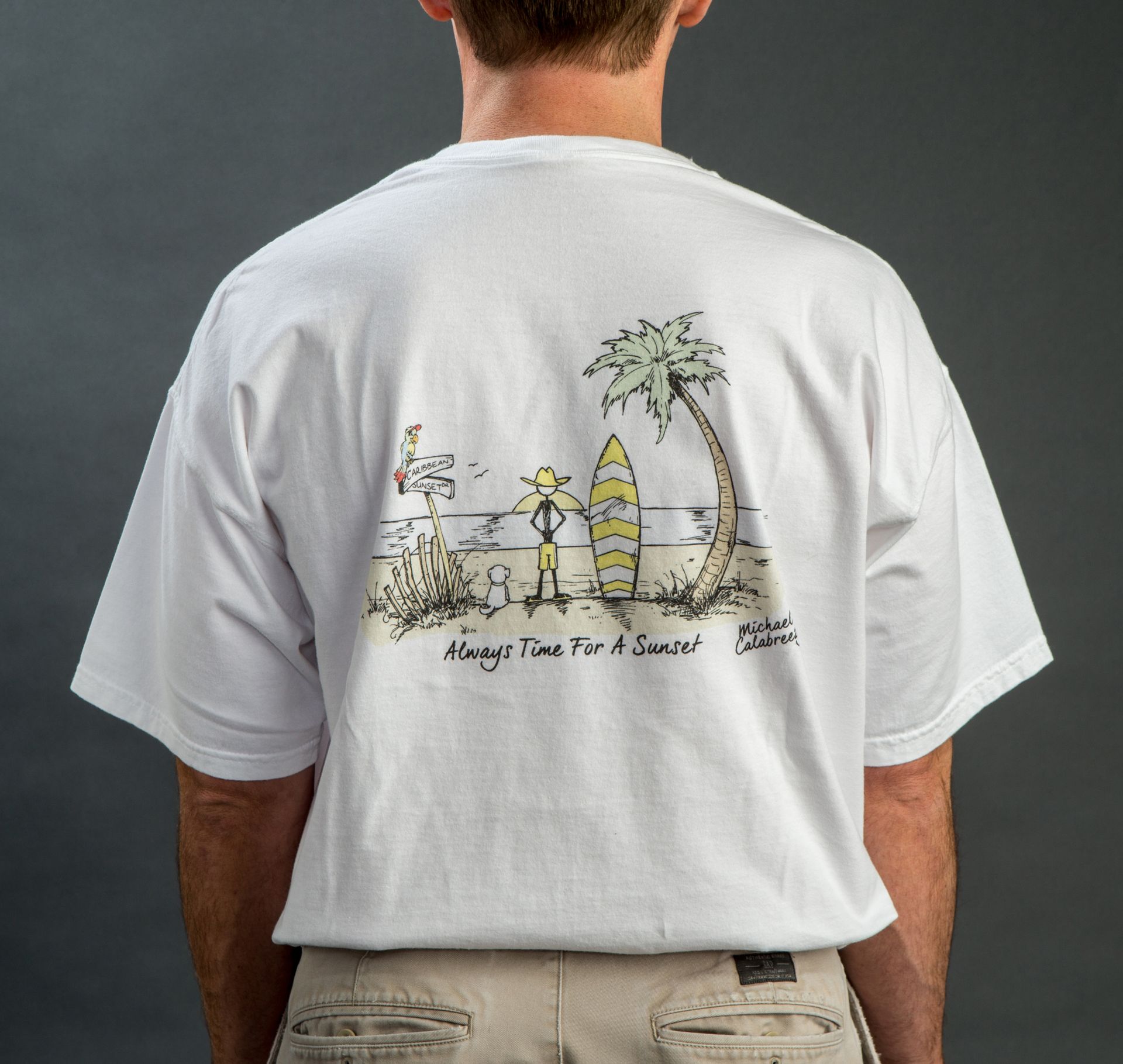 Two people on a beach wearing white t-shirts with cartoon graphic and text.