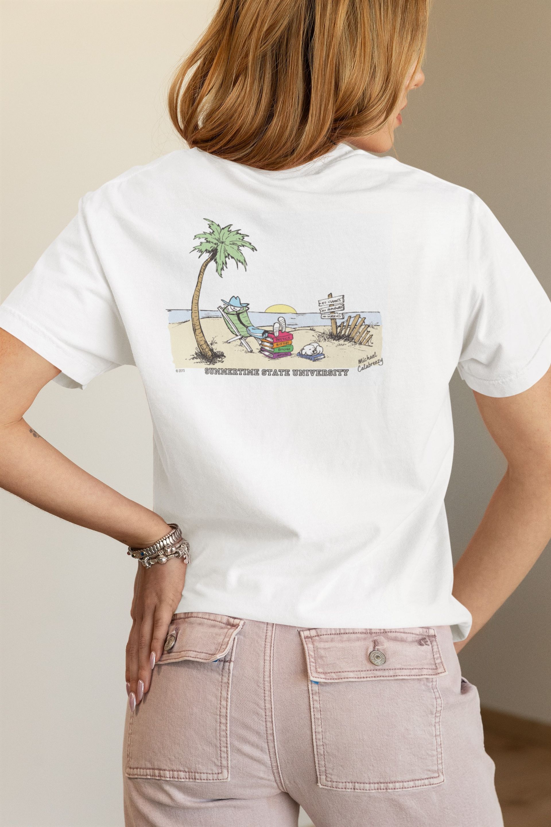 Woman in white t-shirt with beach graphic on back, wearing striped pants.