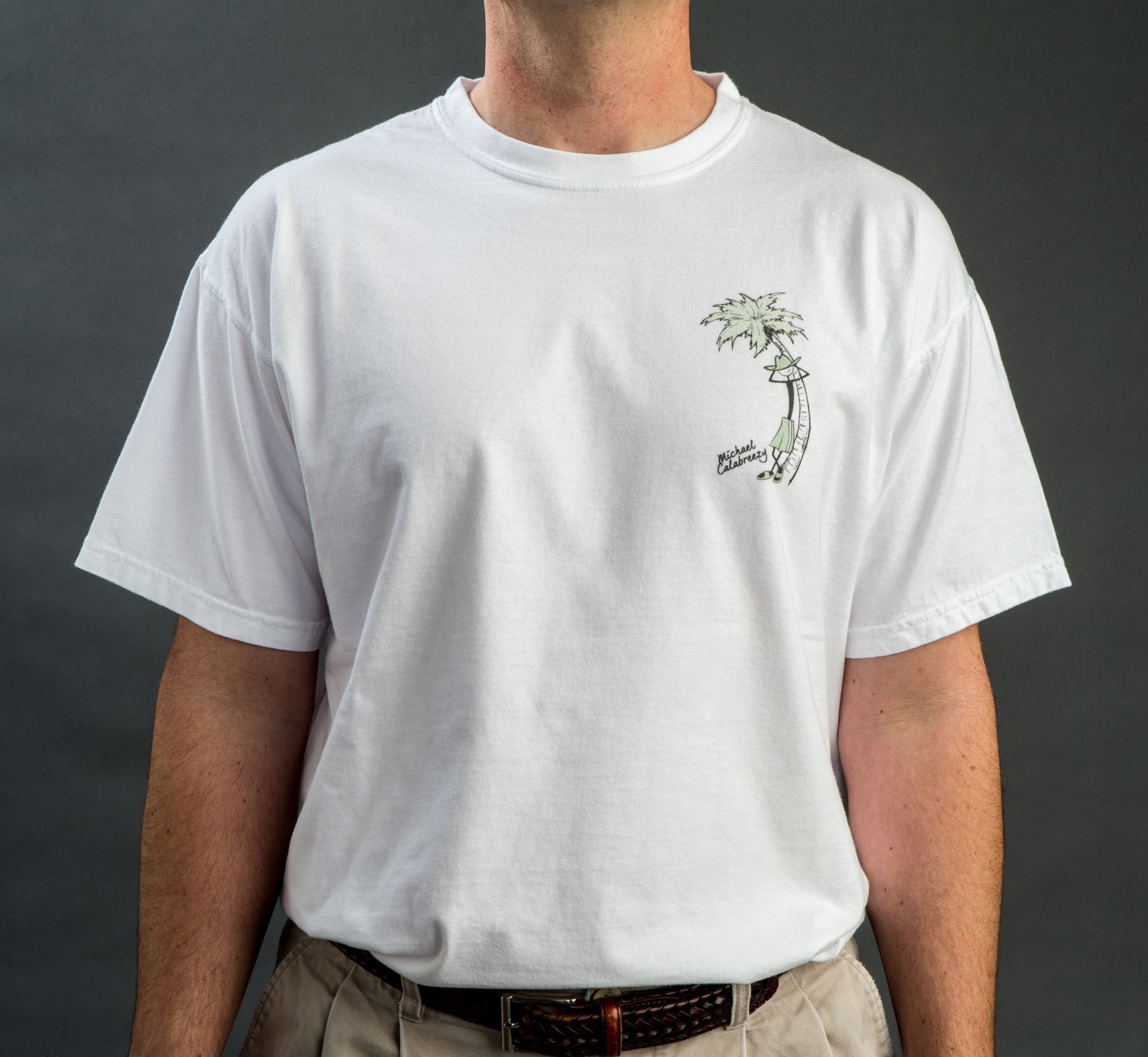 Woman on beach wearing a white t-shirt and beaded necklace. Turquoise ocean in the background.