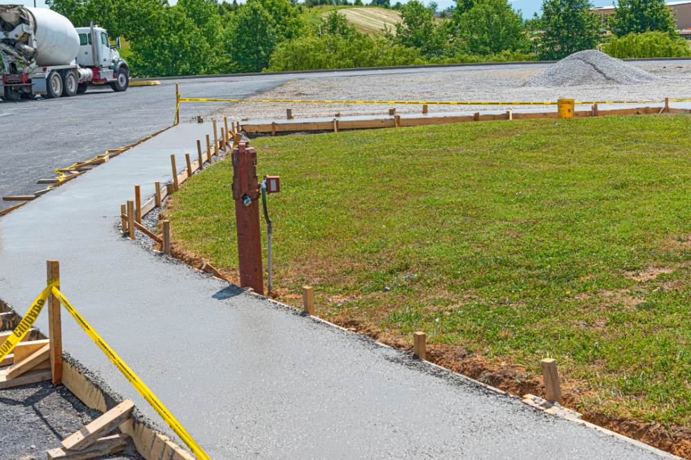 A concrete walkway is being built in a field with a cement truck in the background.