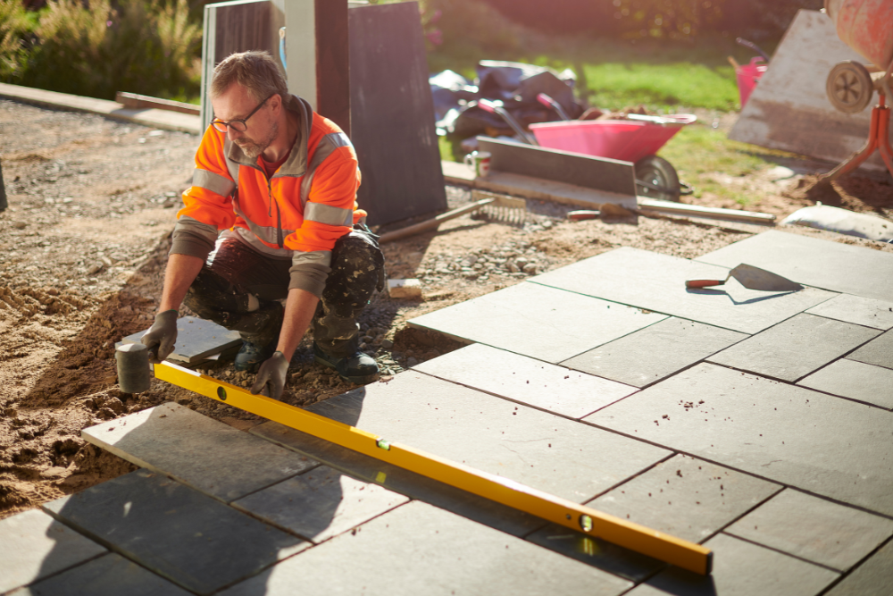 A man is using a level to check the level of a patio.
