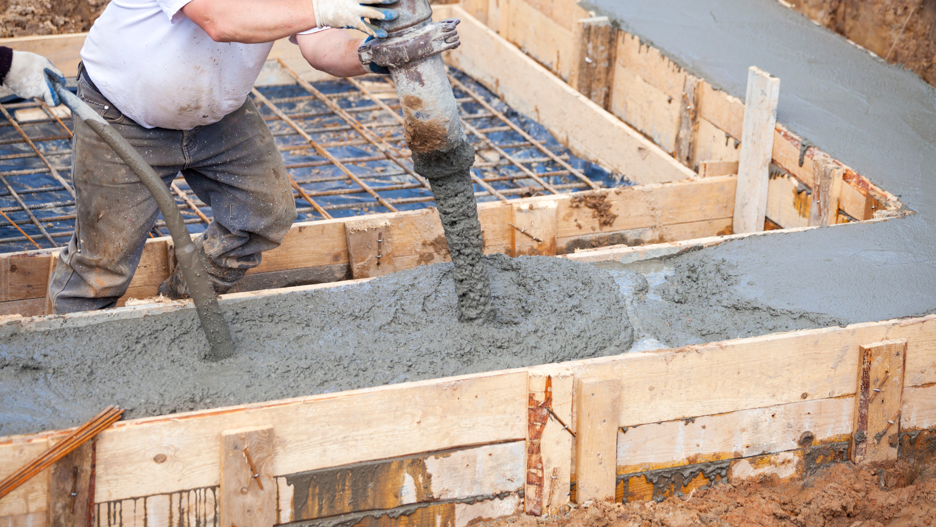 A man is pouring concrete into a concrete foundation.