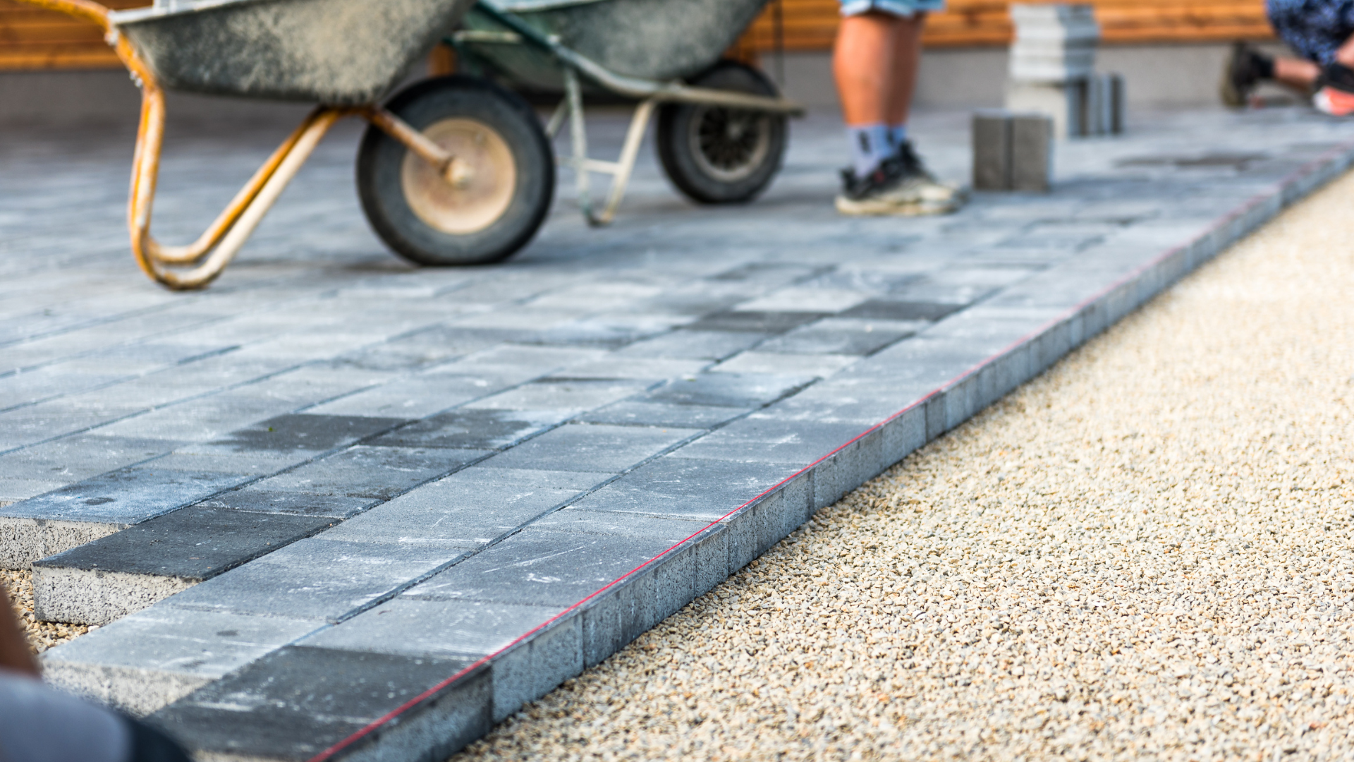 A wheelbarrow is being pushed down a brick walkway.