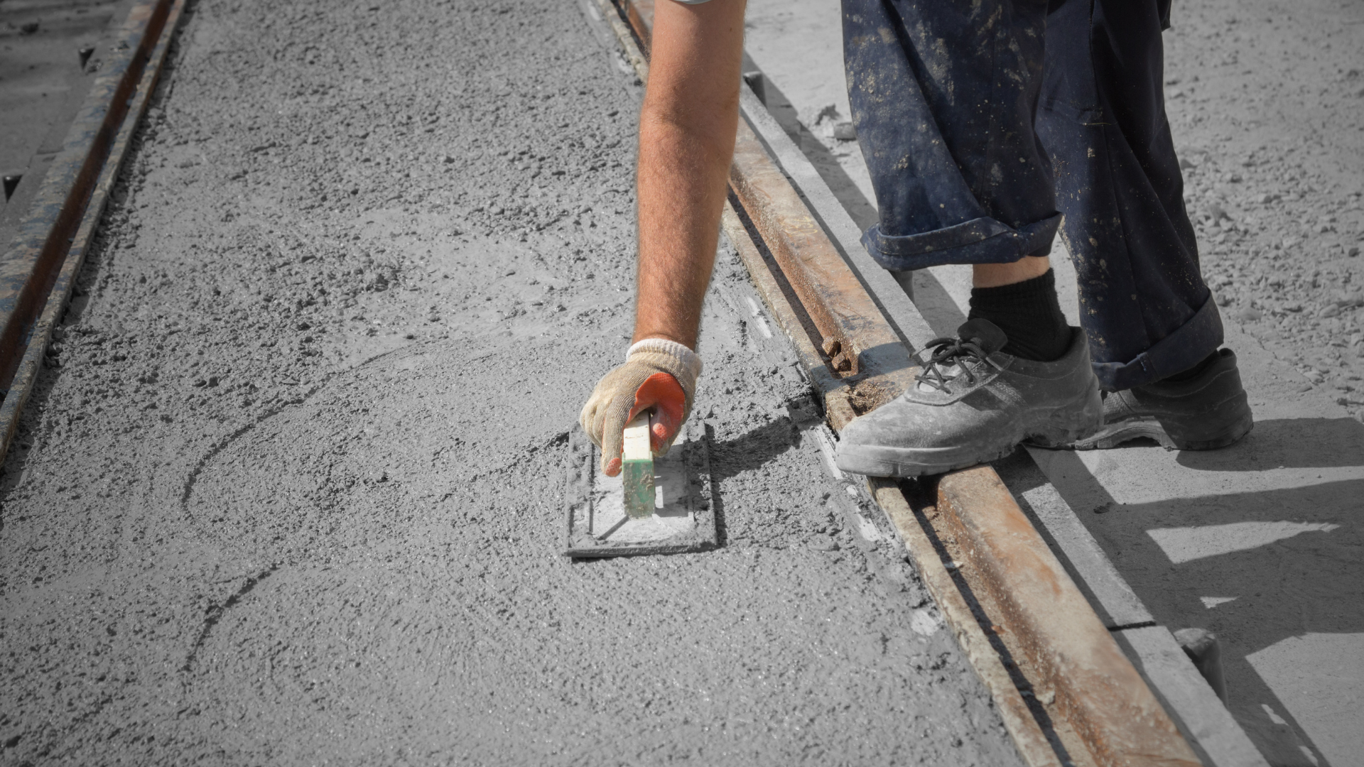 A person is using a trowel to spread concrete on a concrete surface.
