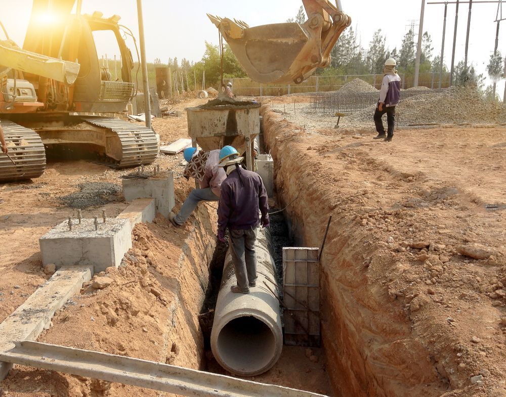 A group of construction workers are working on a pipe in a trench.
