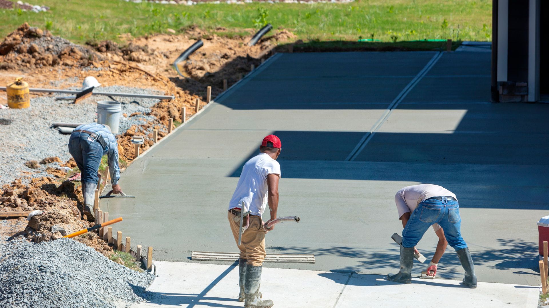 A group of men are working on a concrete driveway.