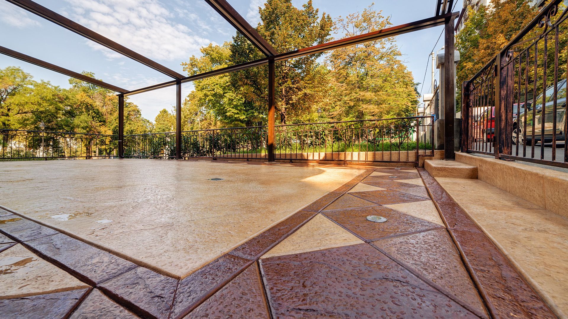 A large patio with a fence and trees in the background.