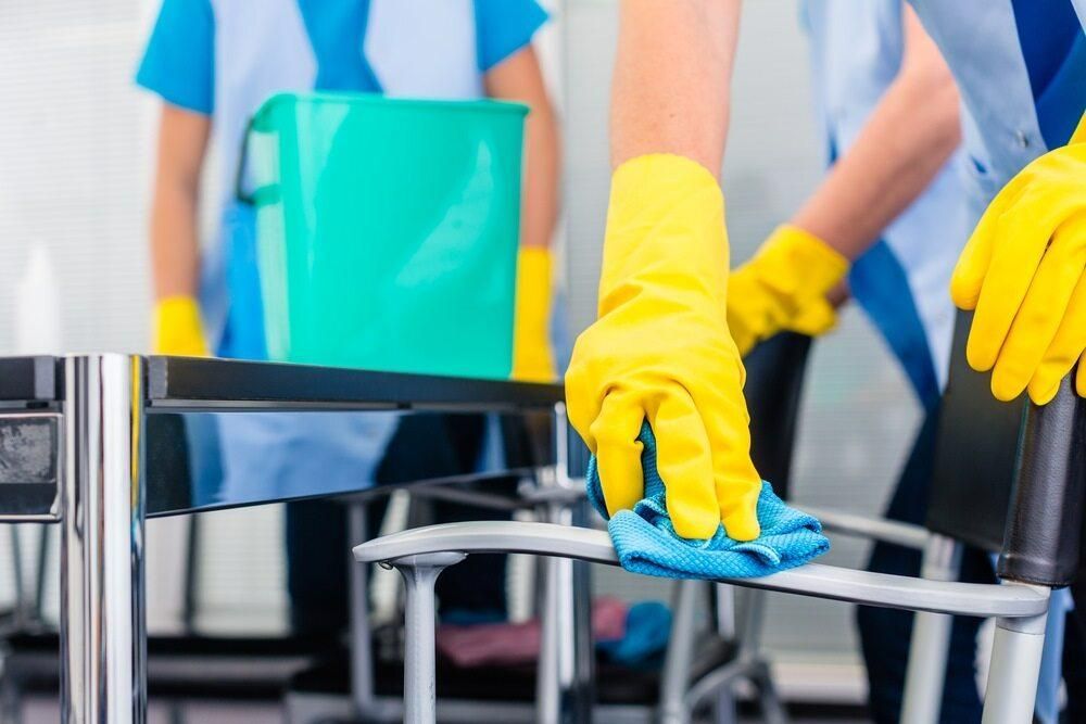 A Person Wearing Yellow Gloves is Cleaning a Table With a Cloth — TPF Industries in Armstrong Beach, QLD