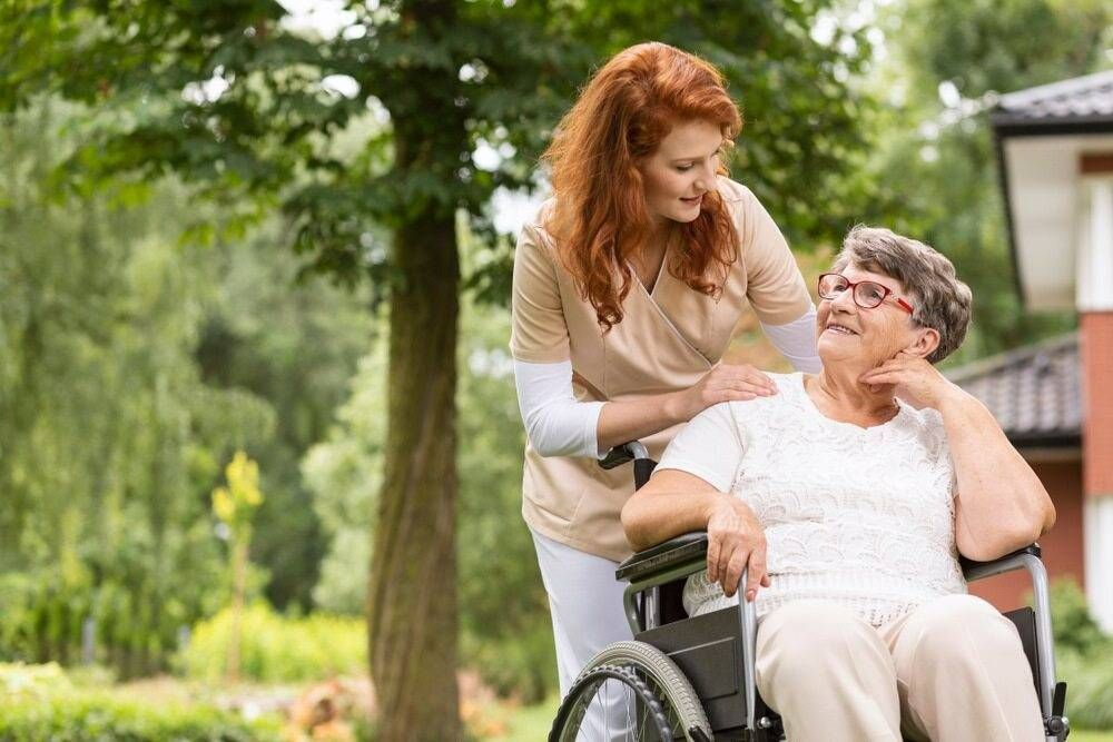A Female Volunteer Helping an Elderly Woman in a Wheelchair in the Garden of an Retirement Home — TPF Industries in Blacks Beach, QLD