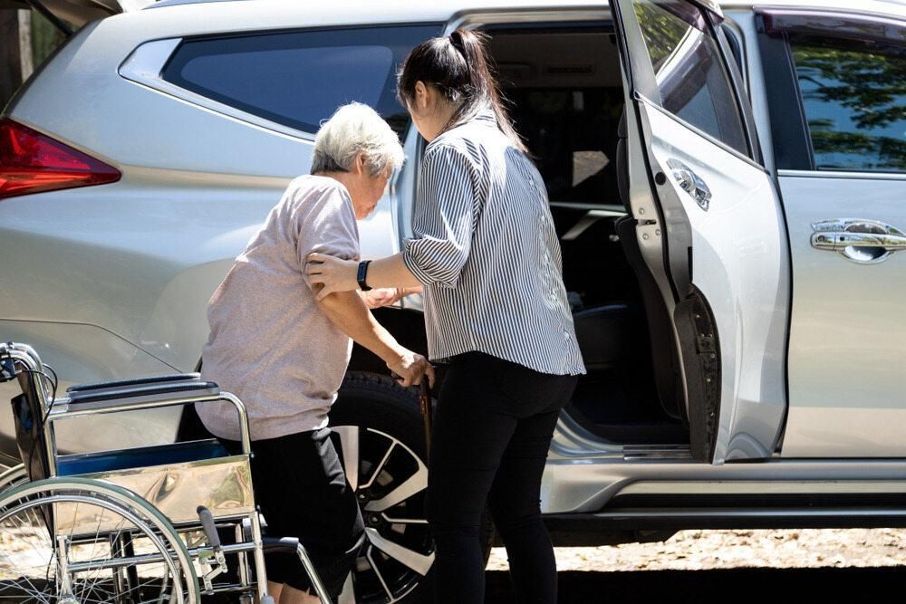 A Woman is Helping an Elderly Woman in a Wheelchair Get Out of a Car — TPF Industries in Blacks Beach, QLD