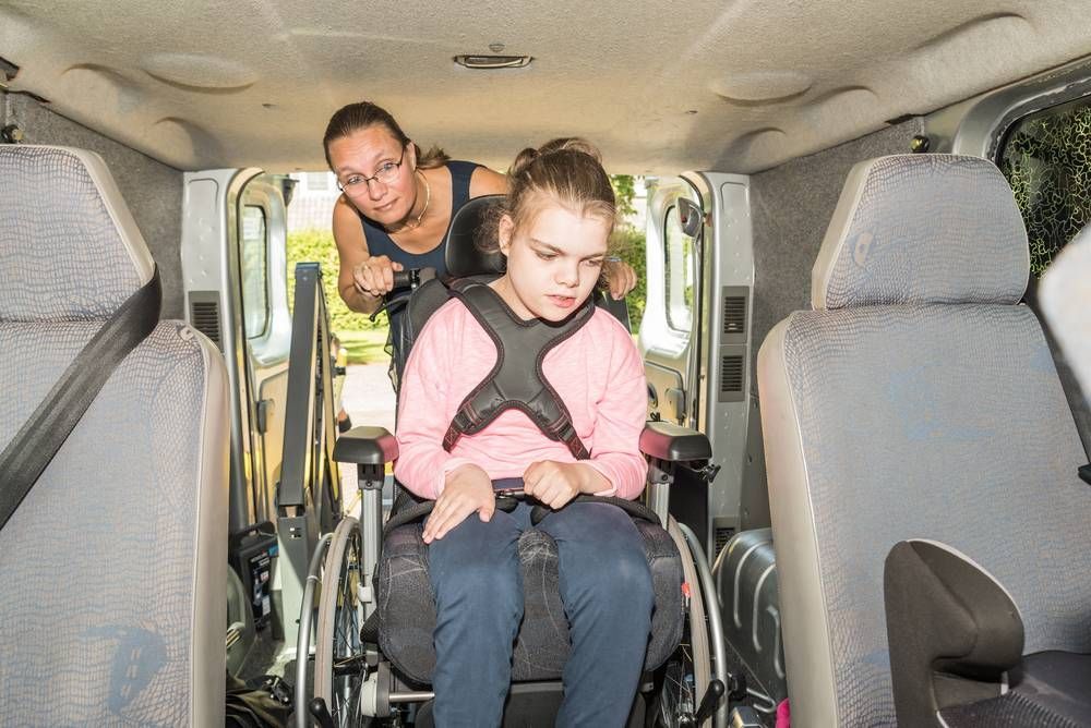 A Woman is Helping a Young Girl in a Wheelchair Into a Van — TPF Industries in Blacks Beach, QLD