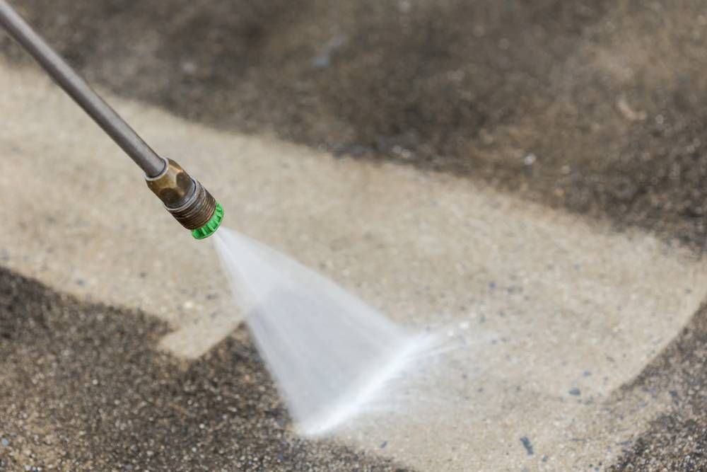 A Person is Using a High Pressure Washer to Clean a Concrete Floor — TPF Industries in Blacks Beach, QLD