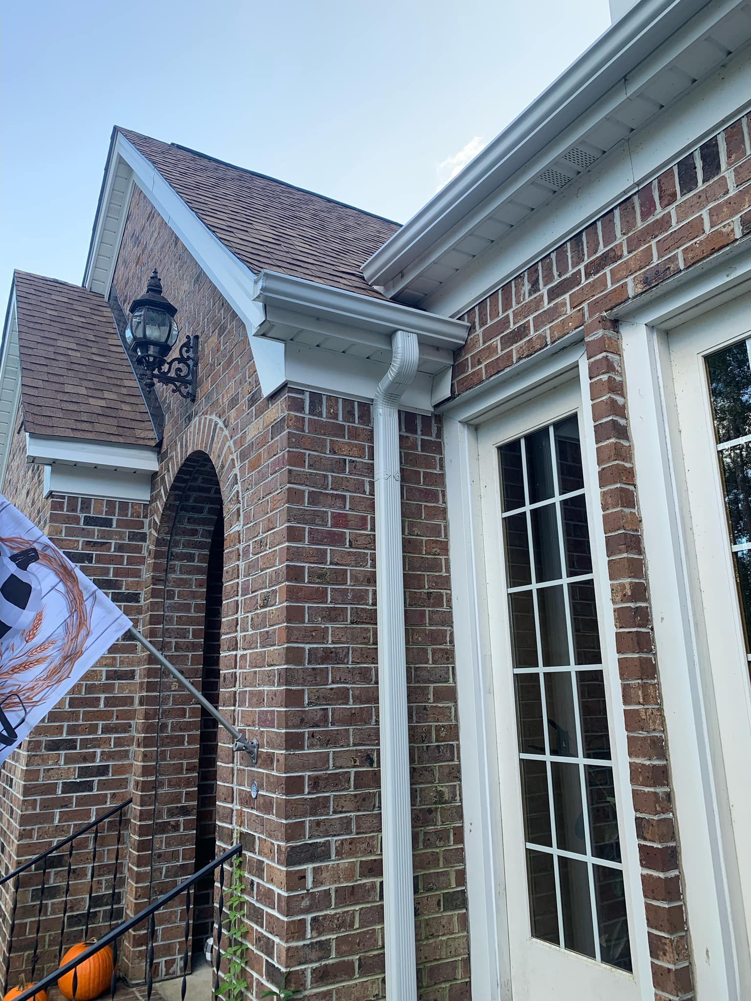 A brick house with white windows and shutters on a sunny day.