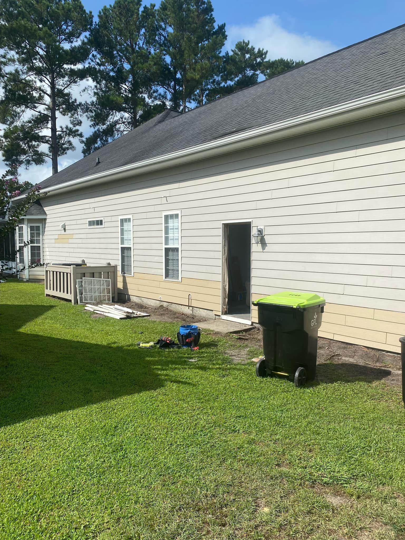 A house with a gray roof is sitting on top of a lush green lawn.