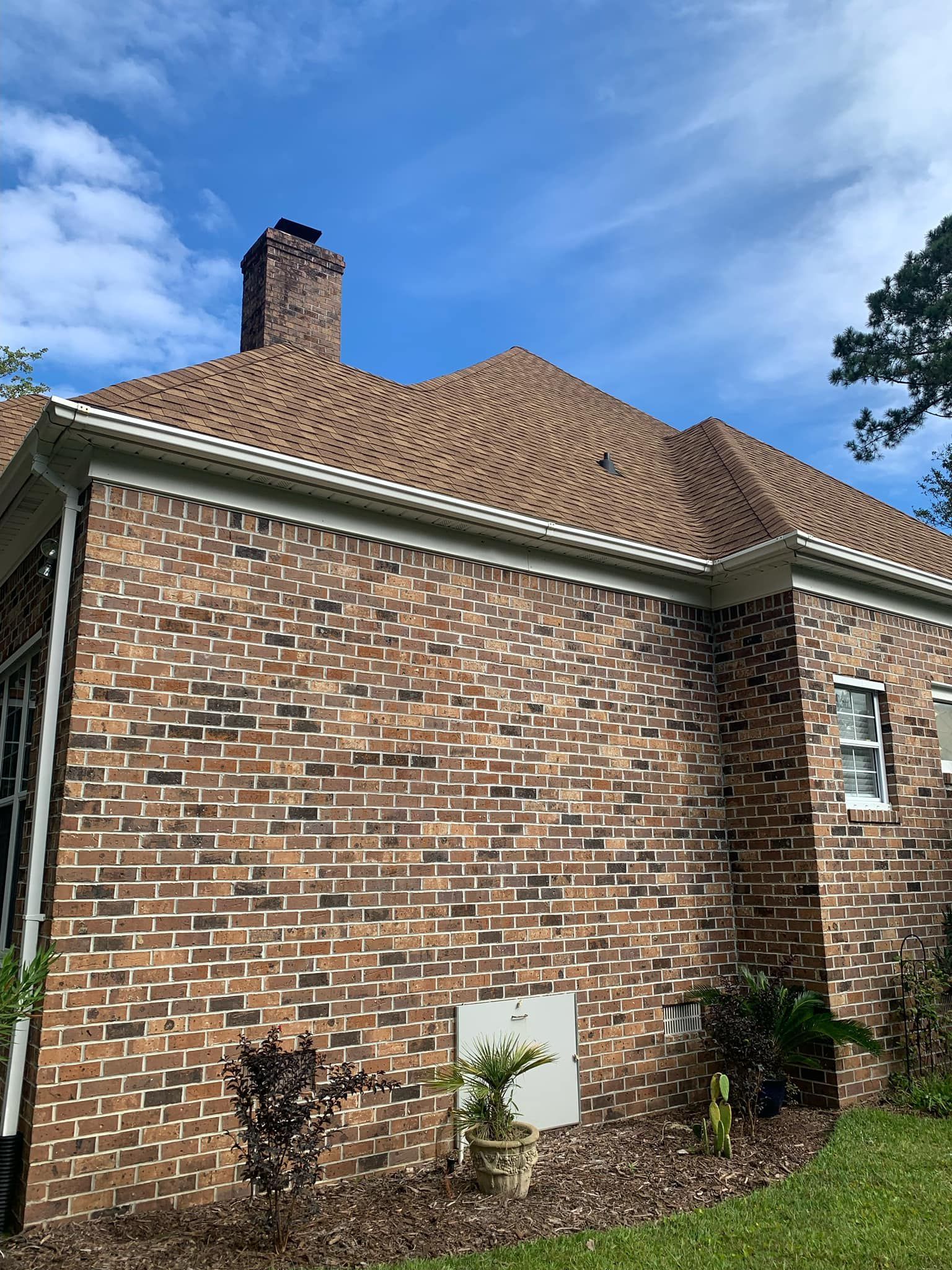 A brick house with a roof that has shingles on it