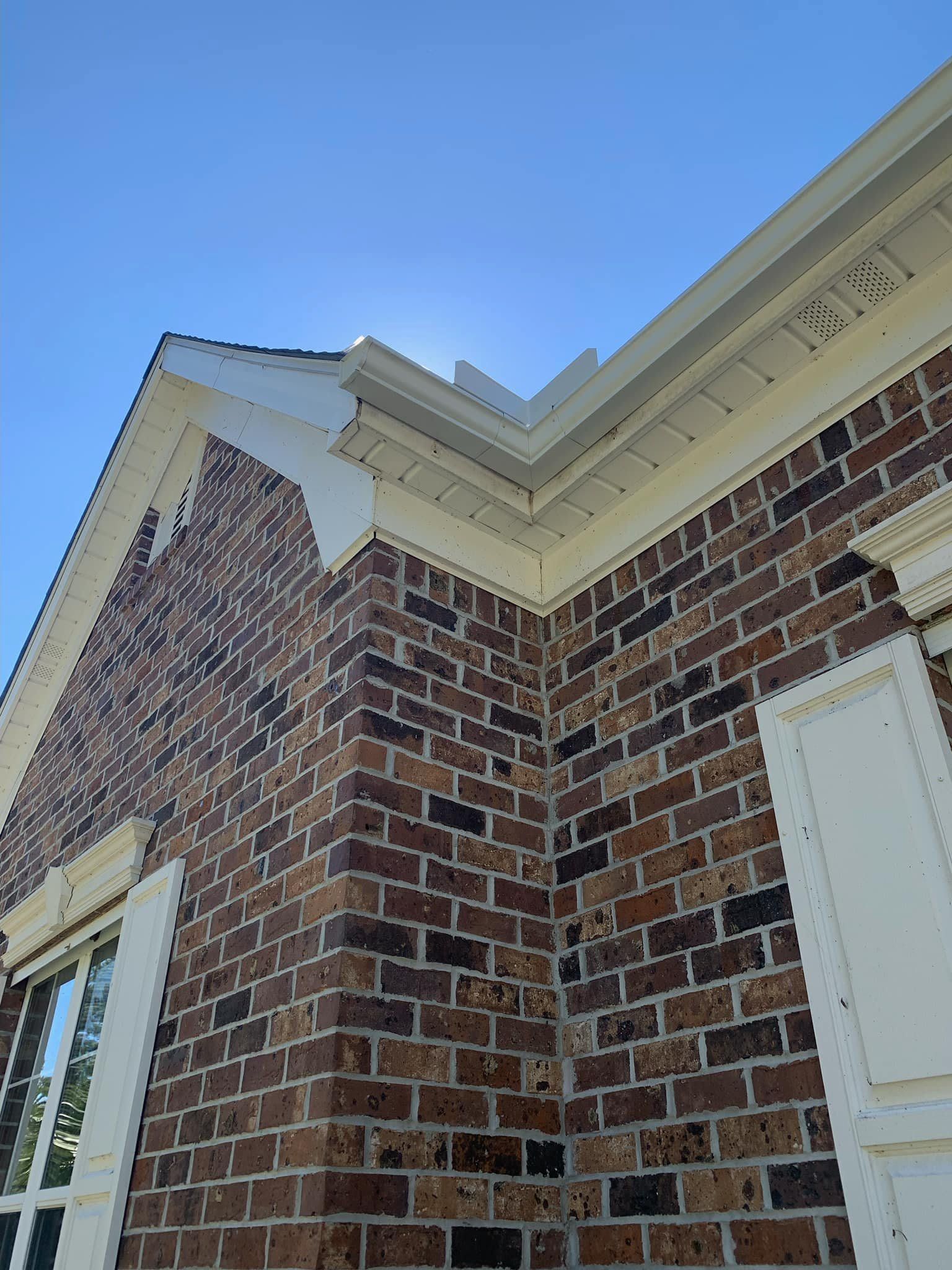 A brick building with white shutters and a blue sky in the background.