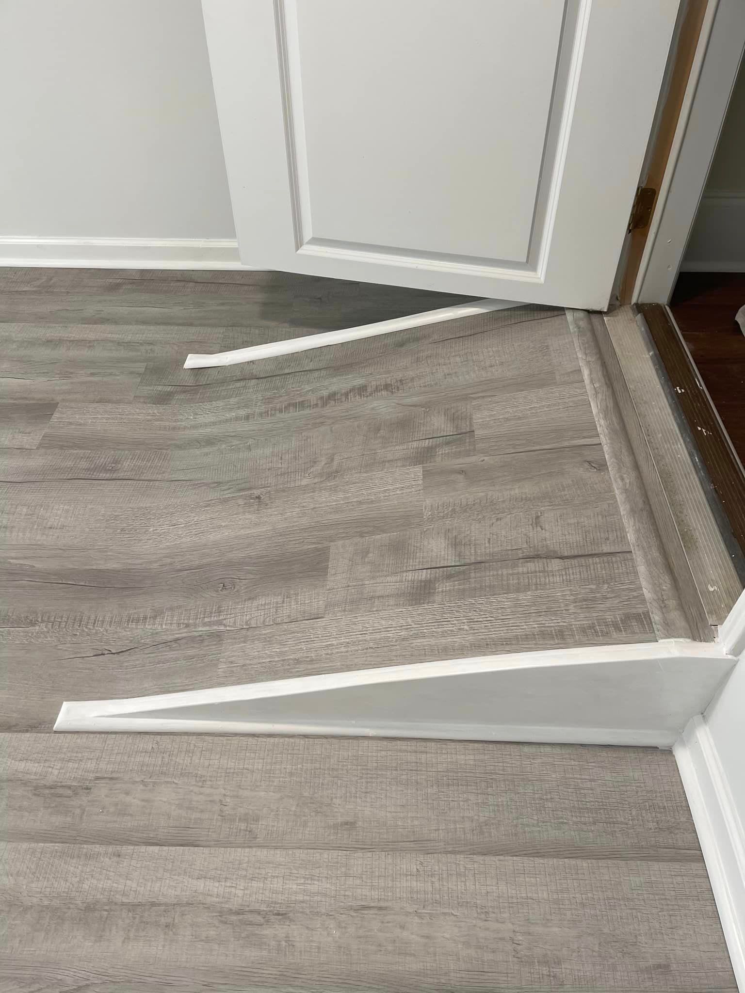 A close up of a wooden floor next to a door.