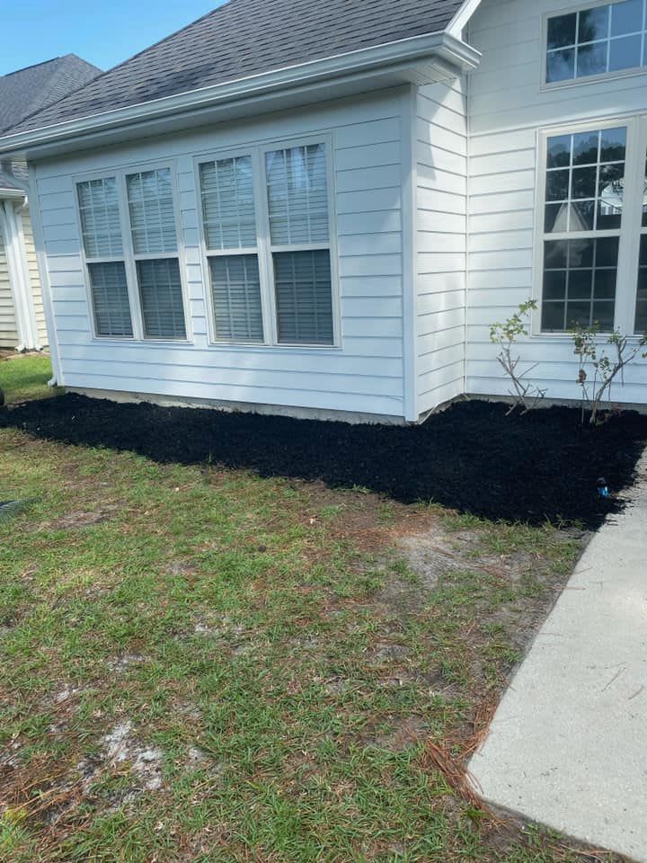 A white house with a gray roof and a fire pit in front of it.
