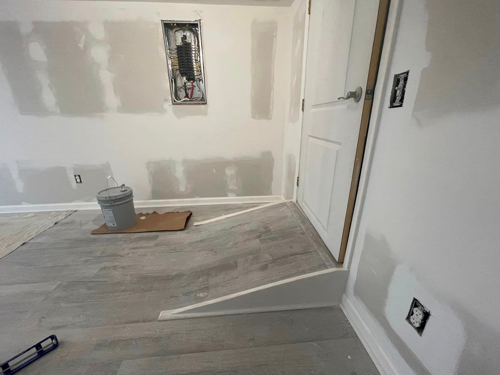 A room with a level on the floor and a bucket on the floor.