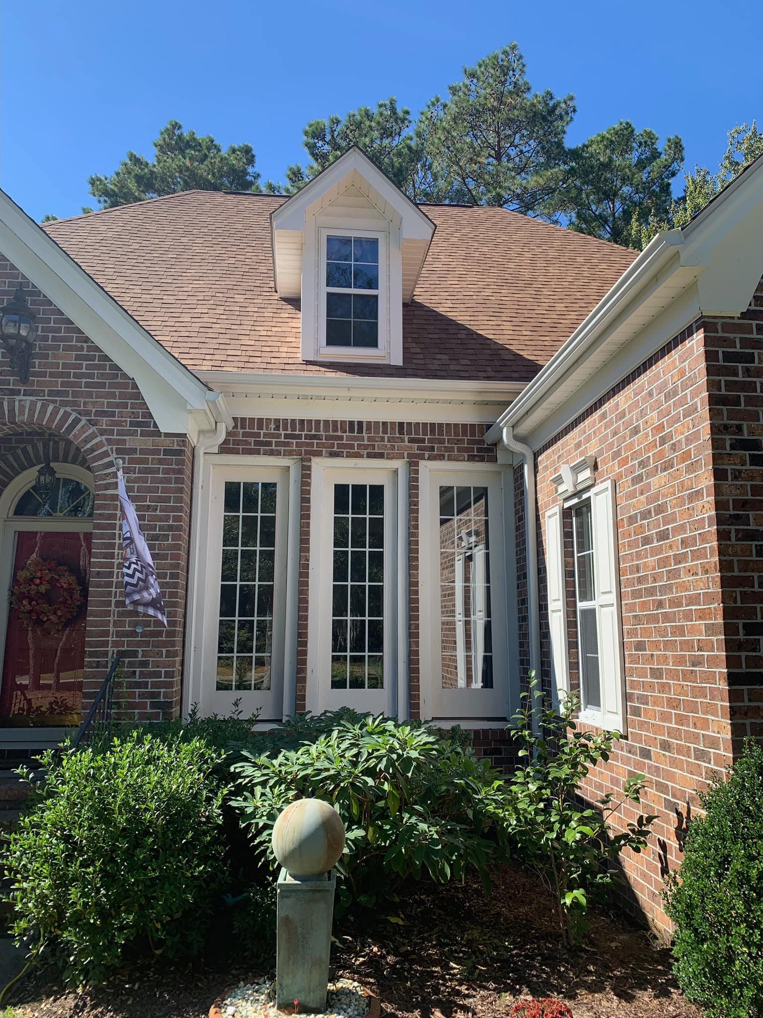 A brick house with a roof that has shingles on it