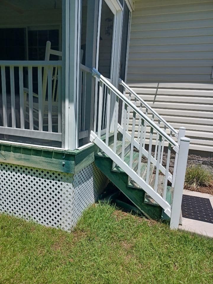 A porch with stairs leading up to it and a white railing.