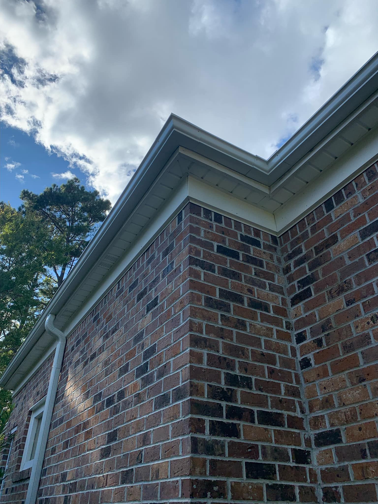 A brick house with a white gutter on the side of it.