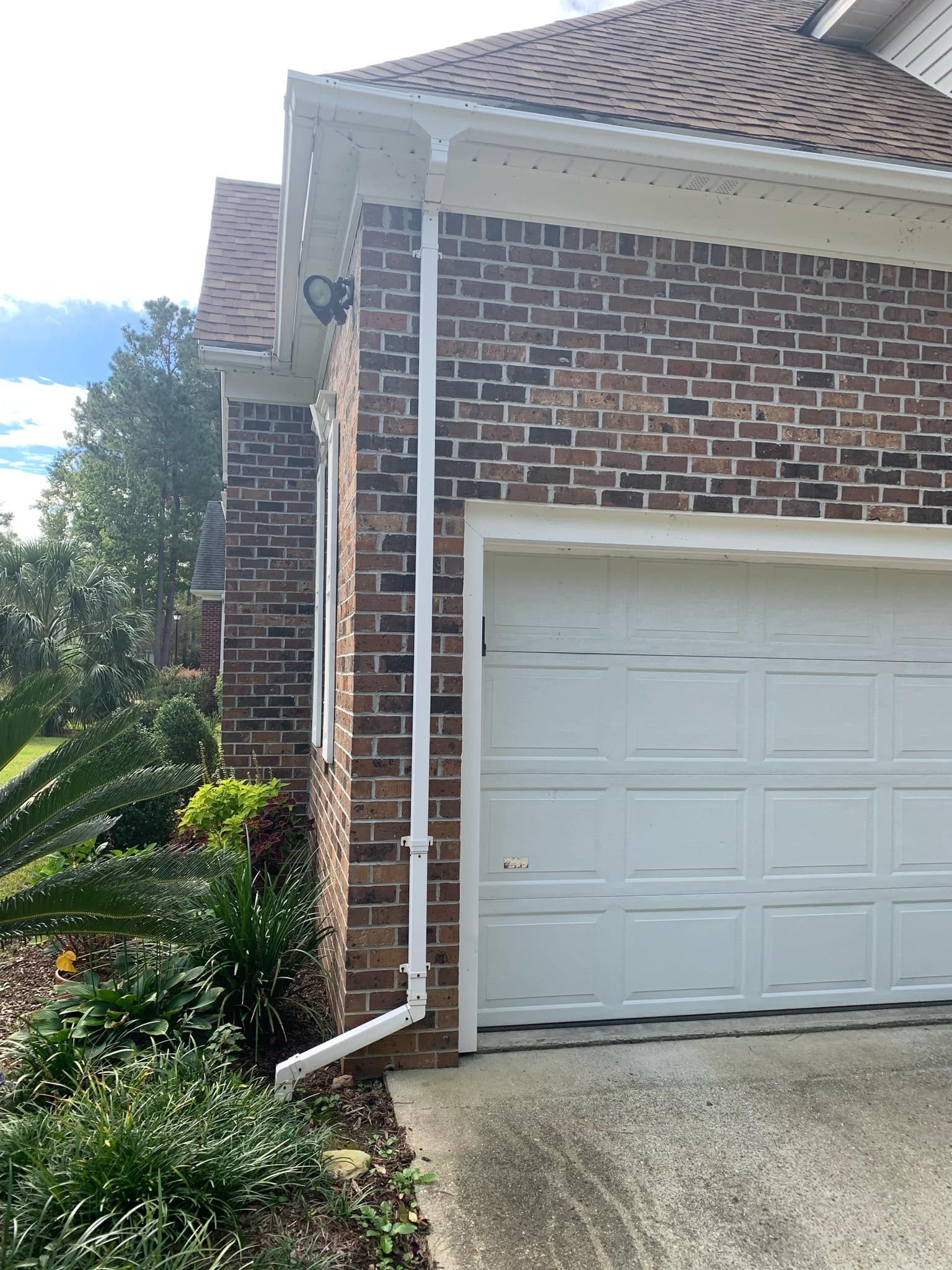 A brick house with a white garage door and a white gutter.