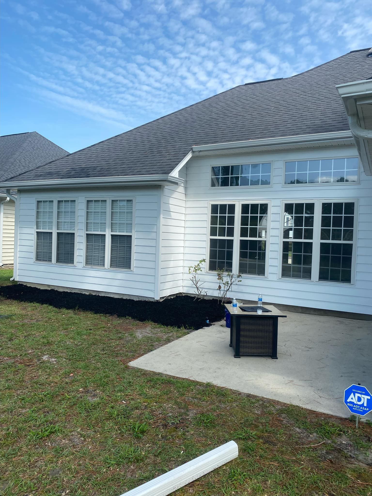 A house with a gray roof is sitting on top of a lush green lawn.