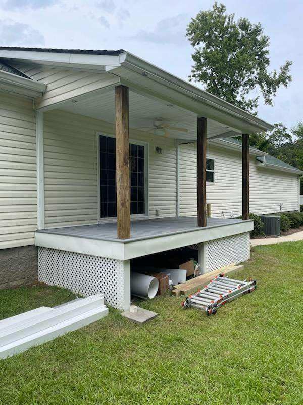 A white house with a porch and a ladder in front of it.